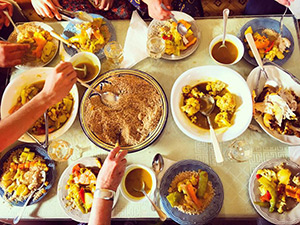 A shot of a table with many bowls and hands scooping the food