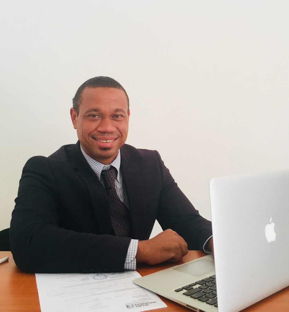 Smiling man in business suit sits at computer