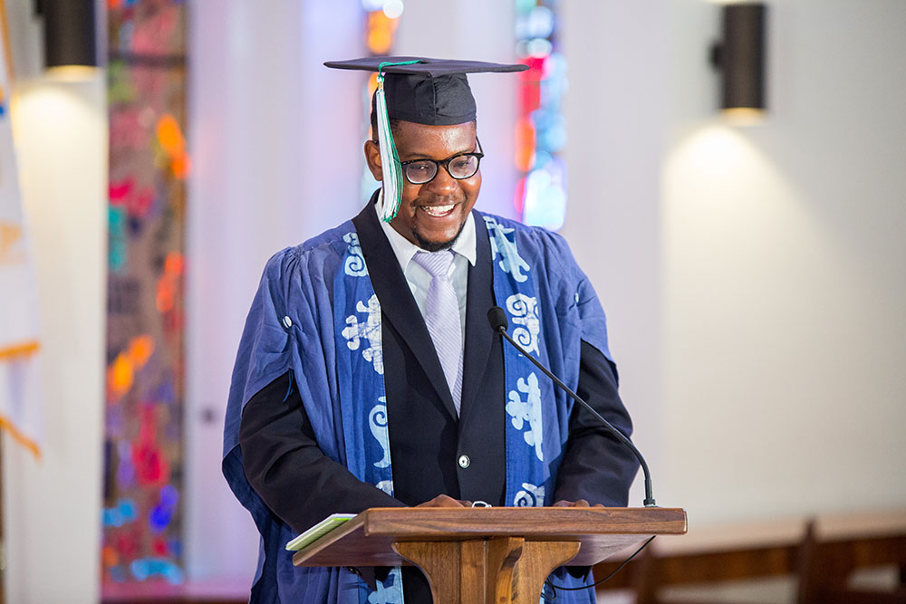 A student dressed up in for commencement, standing at a podium