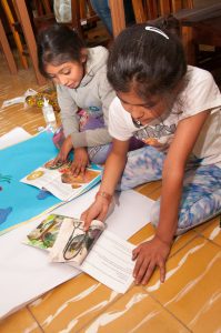 Two girls sit on a library floor, reading books