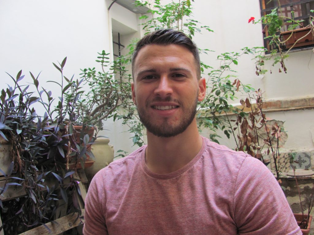 Young man smiles in courtyard