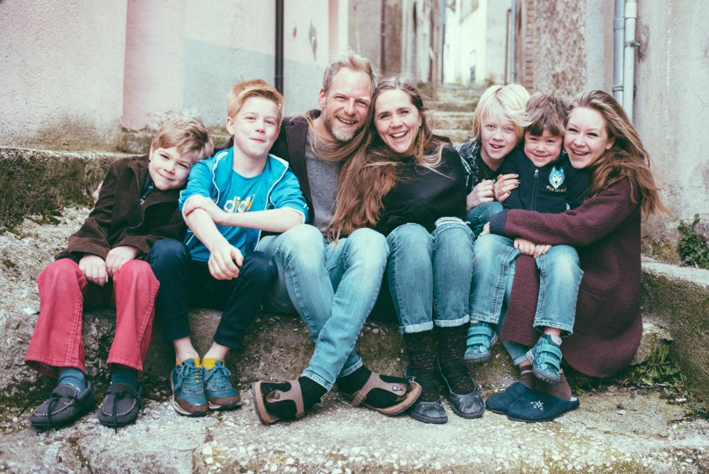 A family of seven pose sitting and smiling on a stone step