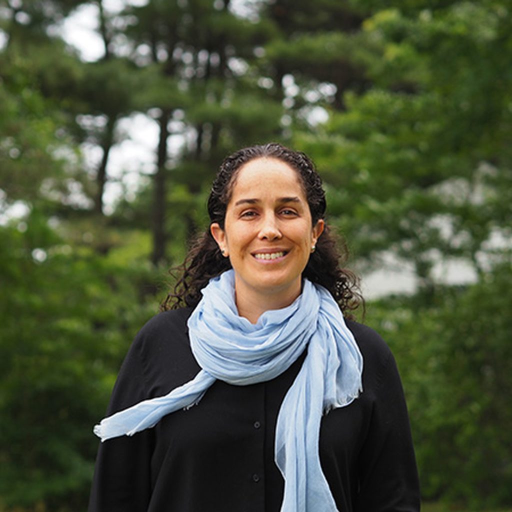 Smiling woman wearing scarf and standing in front of trees