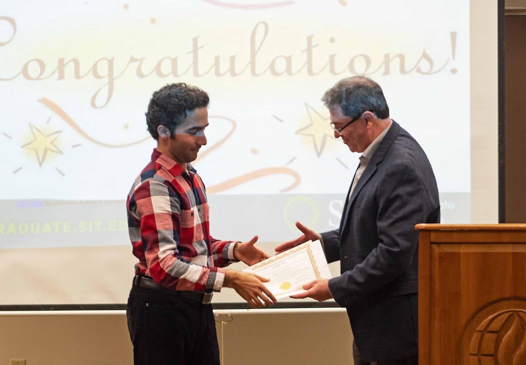 Male student receiving a handshake and certificate from his professor