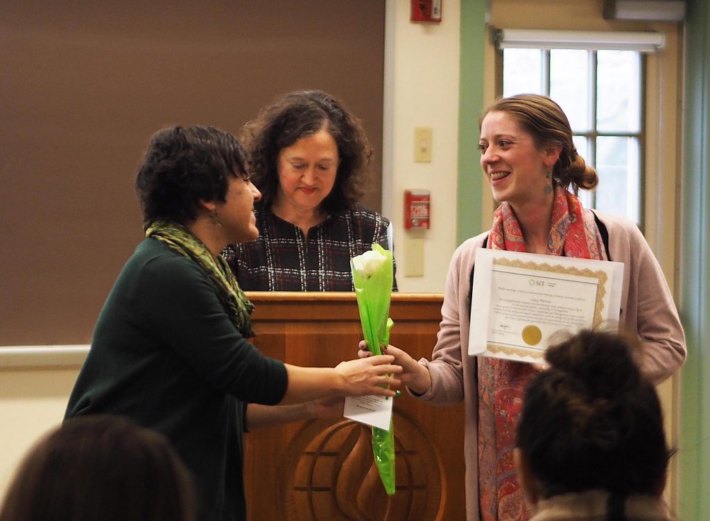 Female student smiles as she receives a rose from alumni director