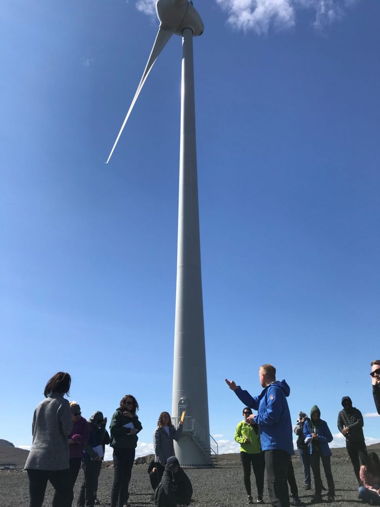 A giant wind turbine draws a group of students.
