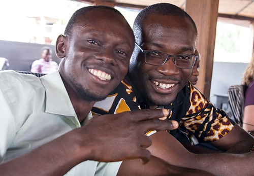 Kwabena and a young man smile at the camera