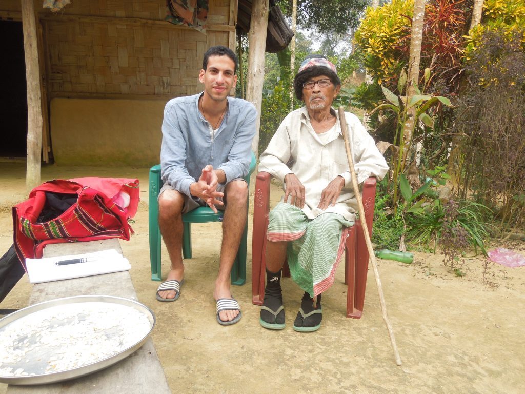 A young man sits with a village elder