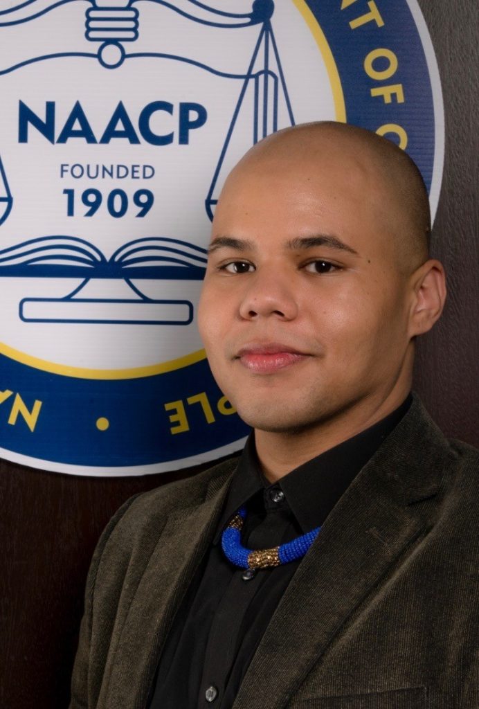 Steffen Gillom stands in front of the NAACP logo