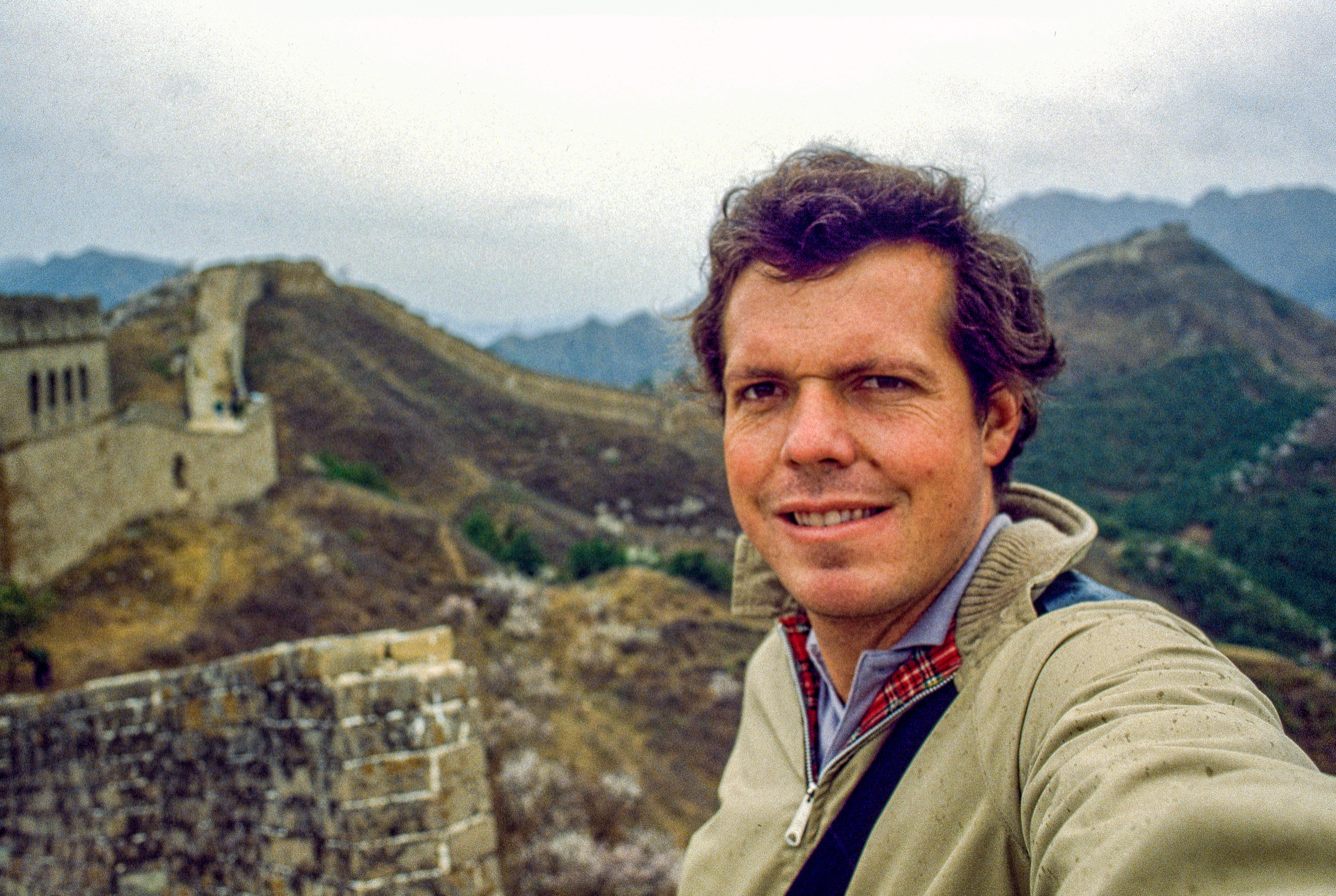 A selfie of a young man with the Great Wall of China in the background.