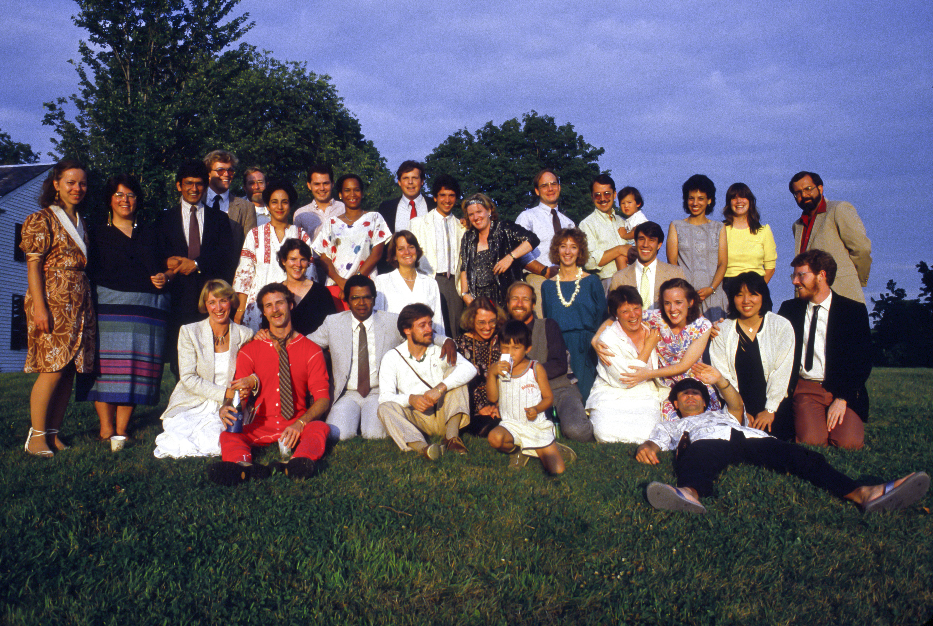 A large group of people pose for a photo on a green lawn.