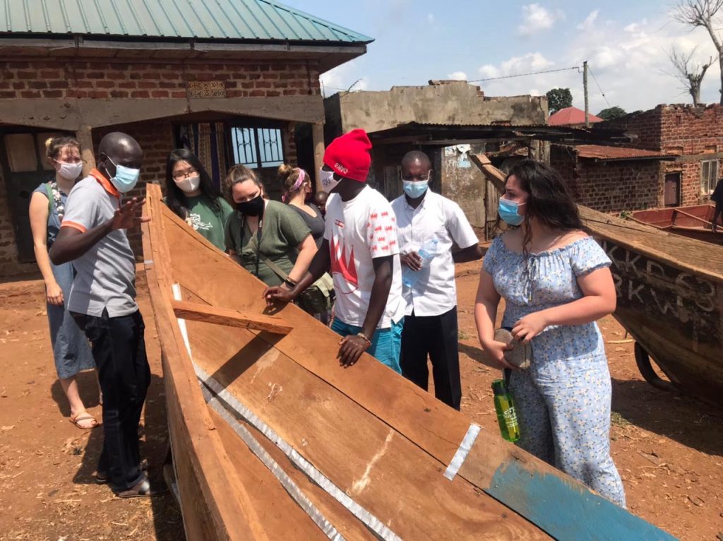 Four U.S. students gather around a boat on dry land as local guides speak about them.