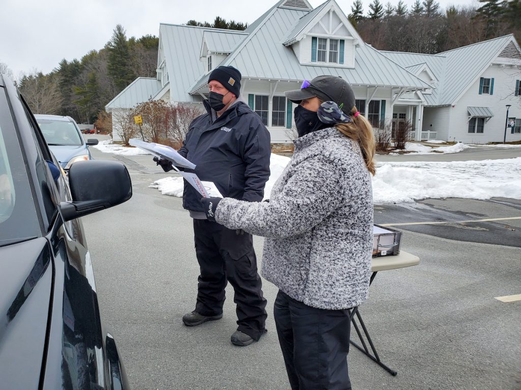 Vermont Foodbank staff members check people in for a food distribution event.