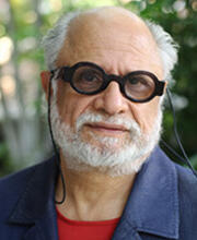 A balding man with gray hair, dark glasses, and a gray beard.