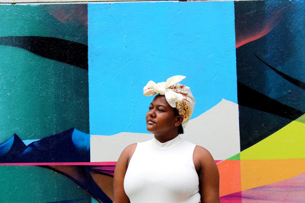 A woman with a white head wrap stands against a colorful background in Argentina.