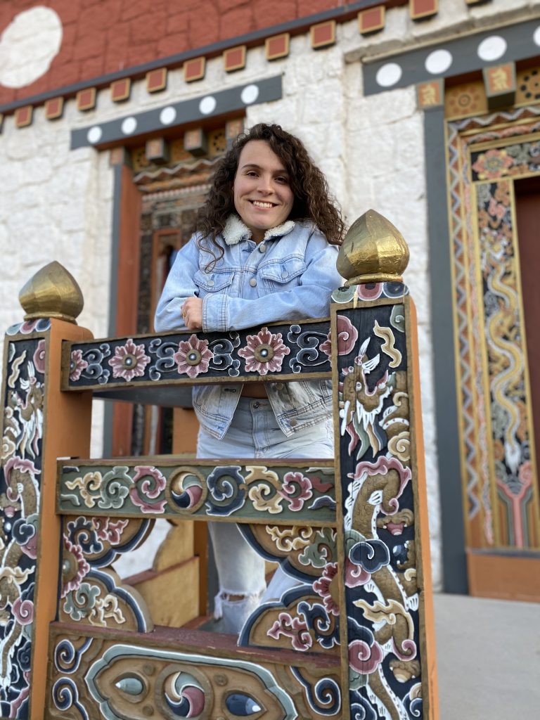 A young woman near a highly decorated wooden structure.