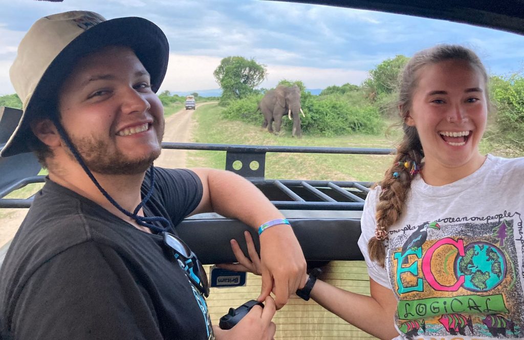 Two young people with an elephant in the background