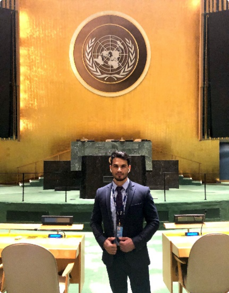 young adult male wearing a suit and tie inside the United Nations conference hall