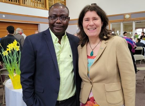 A man and a woman face forward smiling