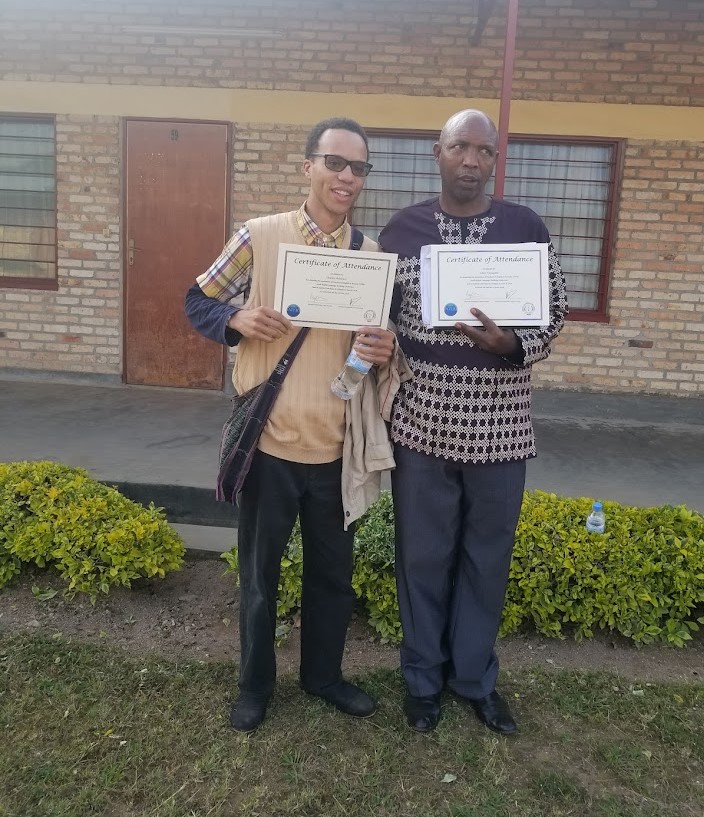 Two men face the camera holding certificates.