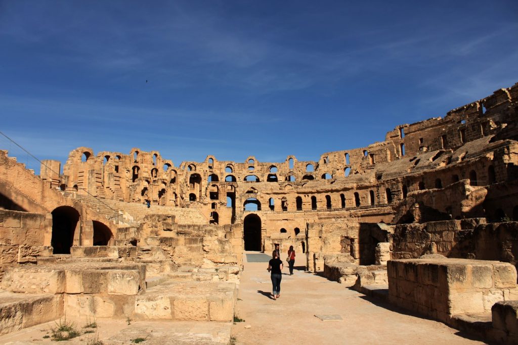 An ancient Roman amphitheater against a bright blue sky