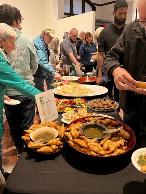 People gather around a long table filled with Afghan food.