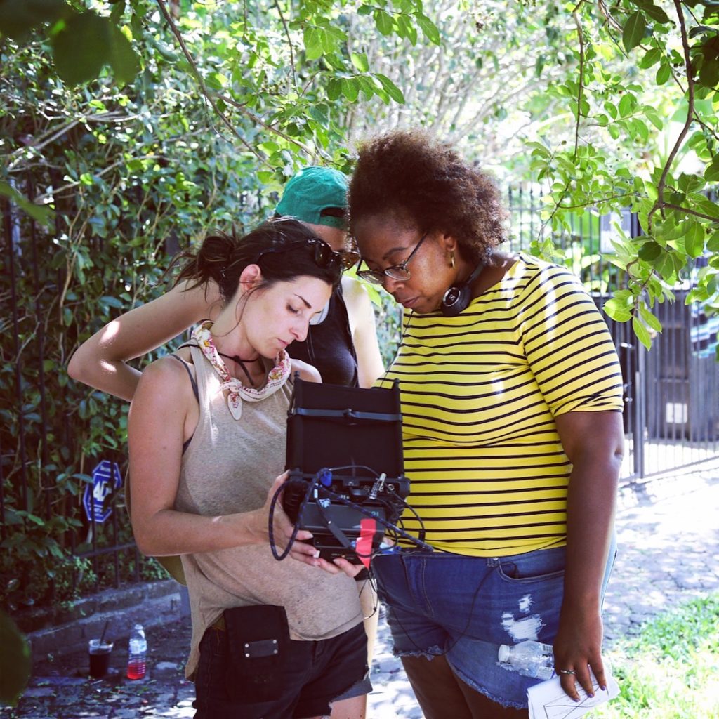 Three women peer intently at a video camera.