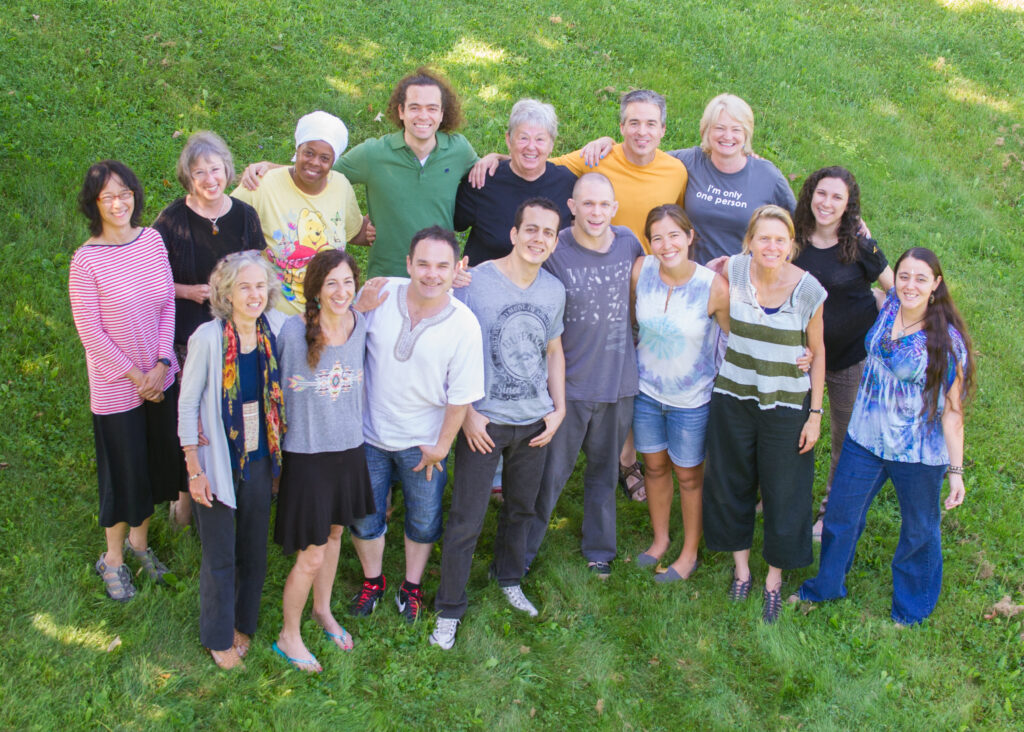 A TESOL cohort of 16 people of diverse ages, genders, and ethnicity look upward and smile. Some have their arms around the shoulders of those next to them.  