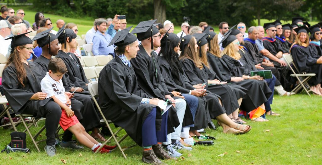 A seated group of graduates wearing black robes and mortar boards 