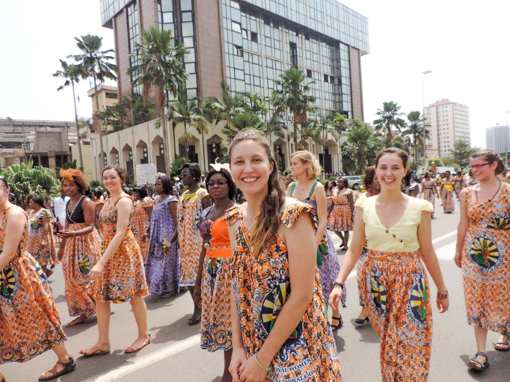 A parade of young people smiling while wearing traditional African clothing.
