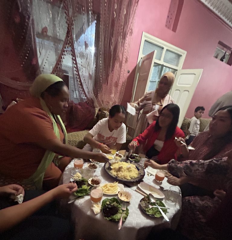 Several people share a meal around a small, round table.