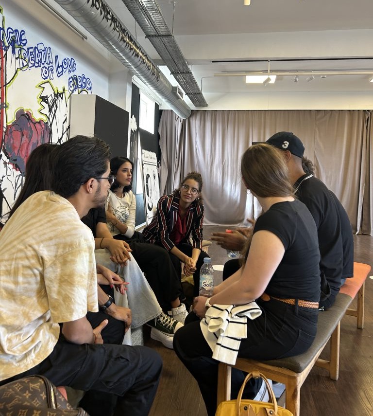 People seated in a circle engage in conversation.